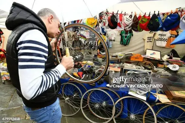 a-man-looks-at-a-vintage-wheel-at-the-bicycle-parts-market-of-the-eroica-montalcino-festive-3...webp